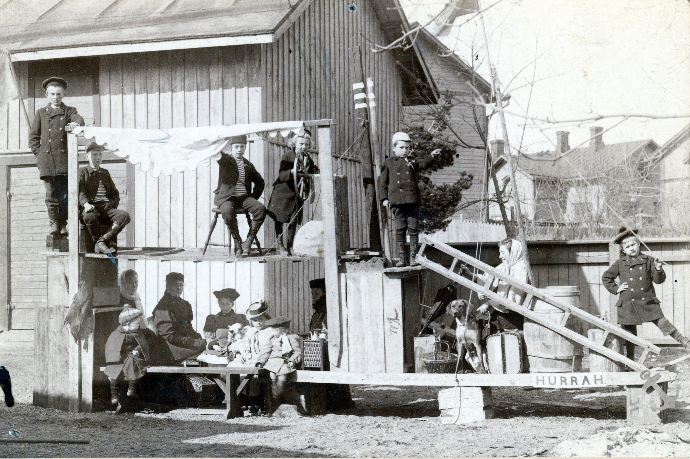 Lapset ja aikuiset ovat rakentaneet laivan HURRAH lankuista ja laatikoista, 1800-lukua. Barn och vuxna har byggt en båt av plankor och lådor på 1800-talet. Children and adults hae built a boat of boards in the 1800s.